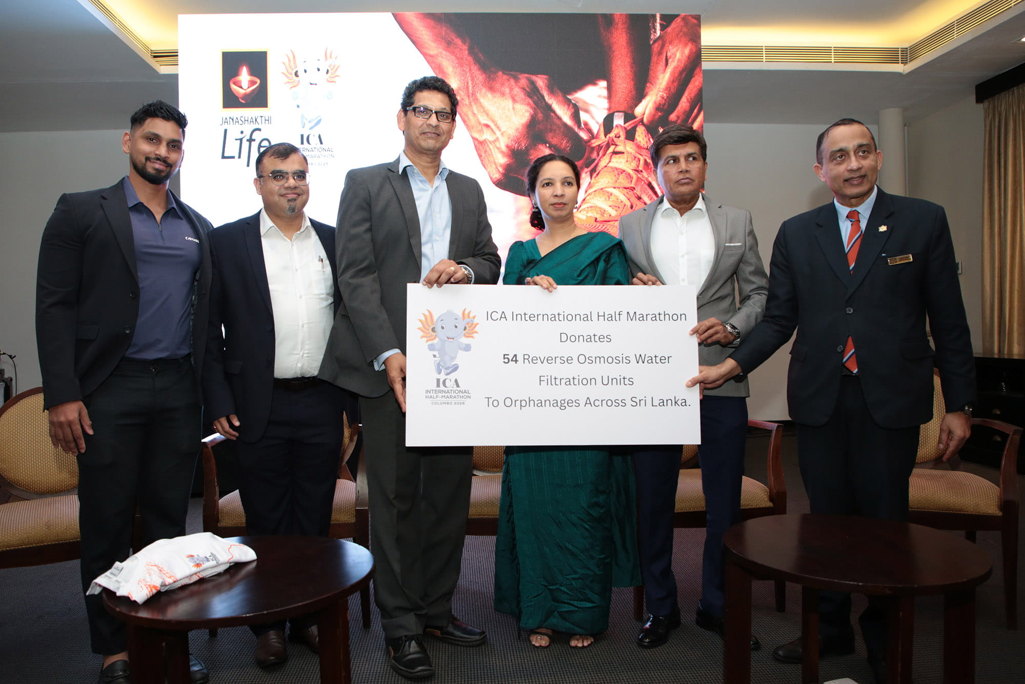 ICA International Half-Marathon representatives and Janashakthi Life hold a board announcing 54 reverse osmosis water filtration units donated to orphanages across Sri Lanka